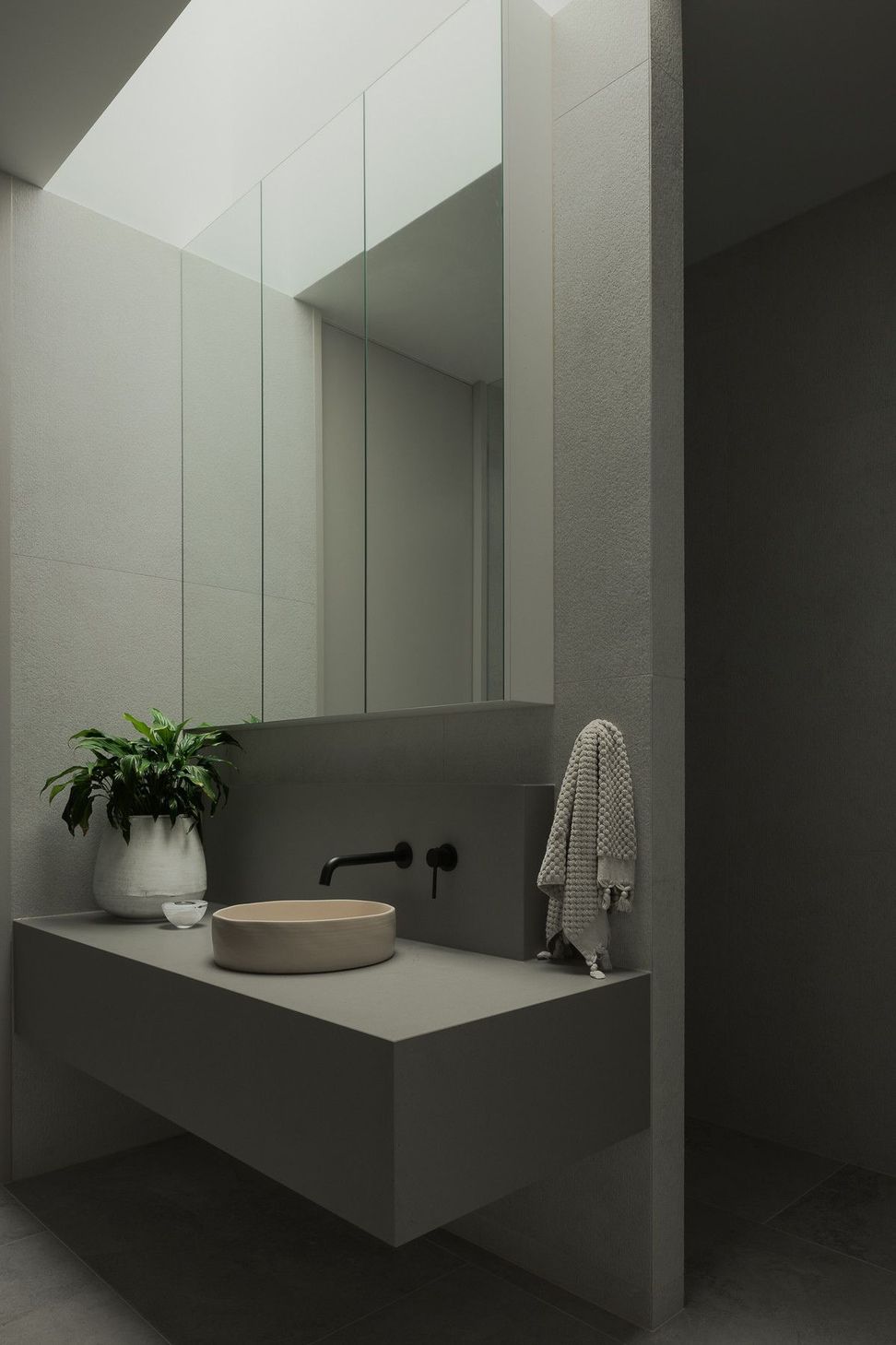 0042 Residence - Bathroom. Pale vanity with a stone basin beneath a skylight.