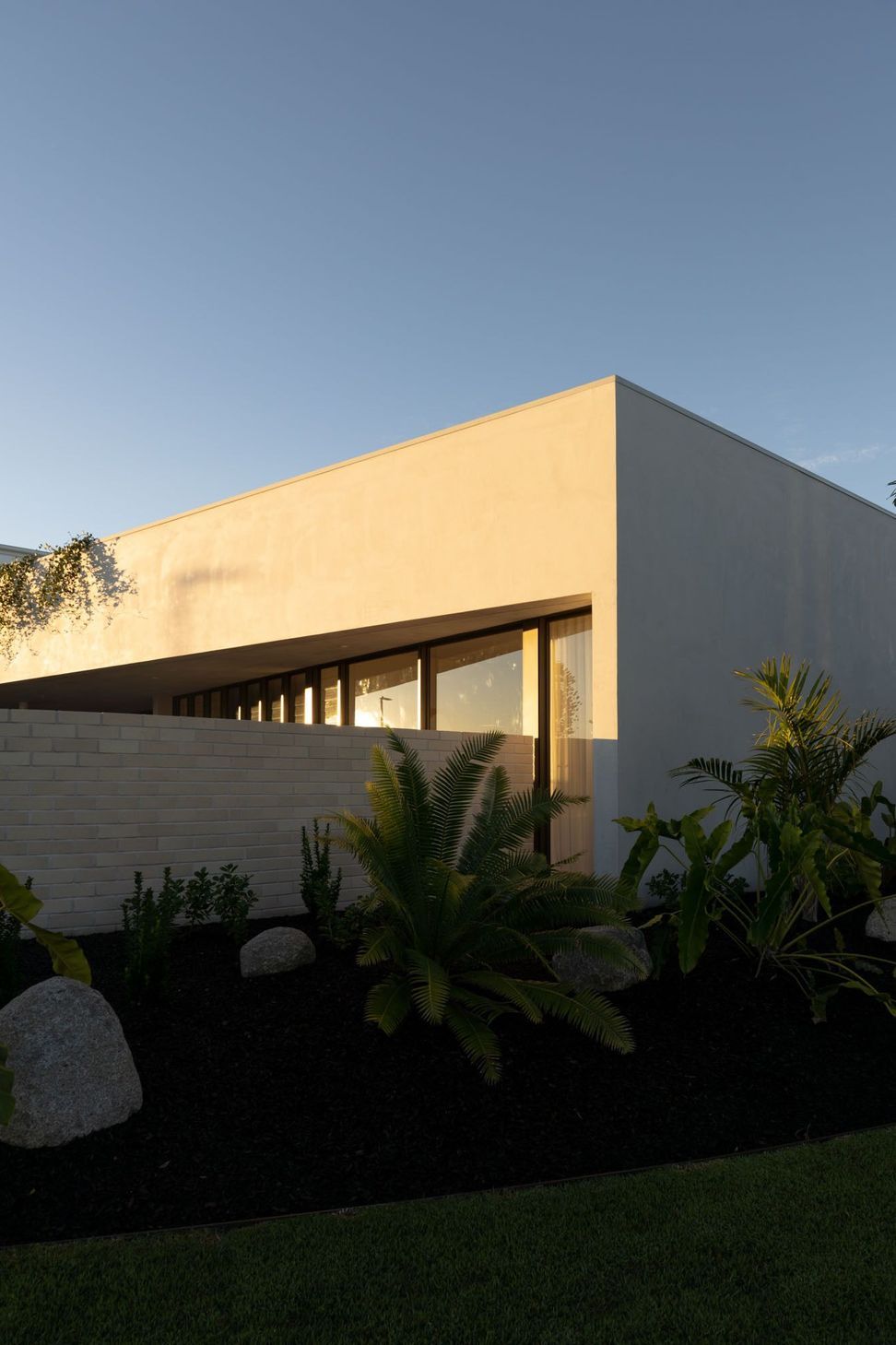 Warrego - Exterior. Rendered parapet and slot windows above tropical planting.