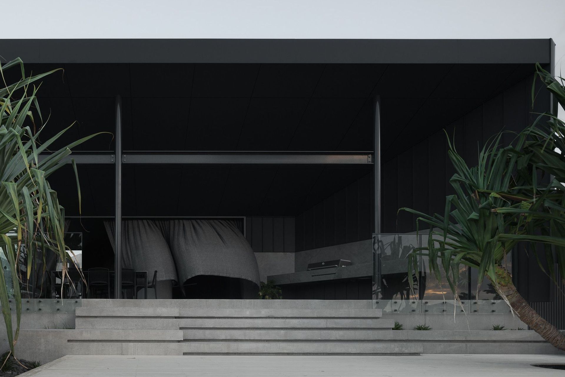 0042 Residence - Patio. Covered outdoor dining framed by the stair and dark cladding.
