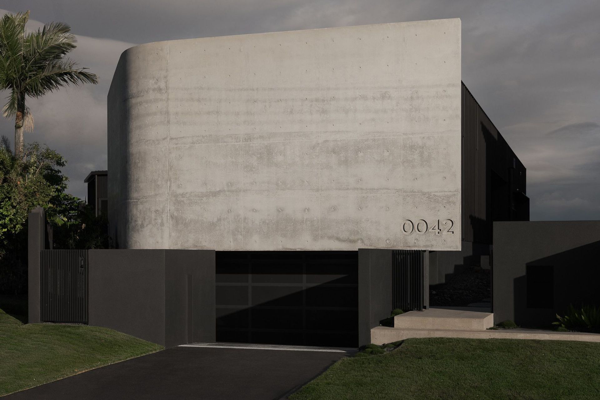 0042 Residence - Exterior. Street elevation with the floating concrete volume above a dark base.