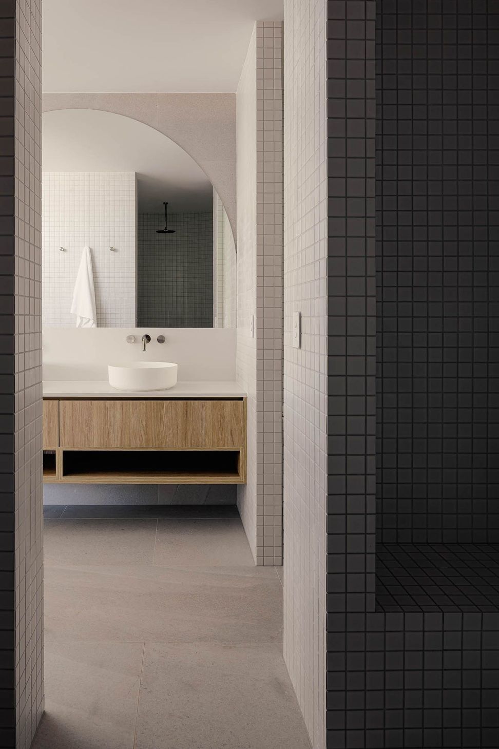 Zaremba Residence - Bathroom. Dark tiled wall beside a timber vanity.