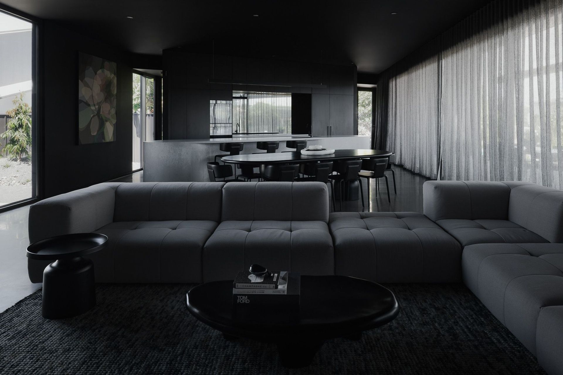 0042 Residence - Living Room. Dark lounge with a deep modular sofa, opening to the dining and kitchen.