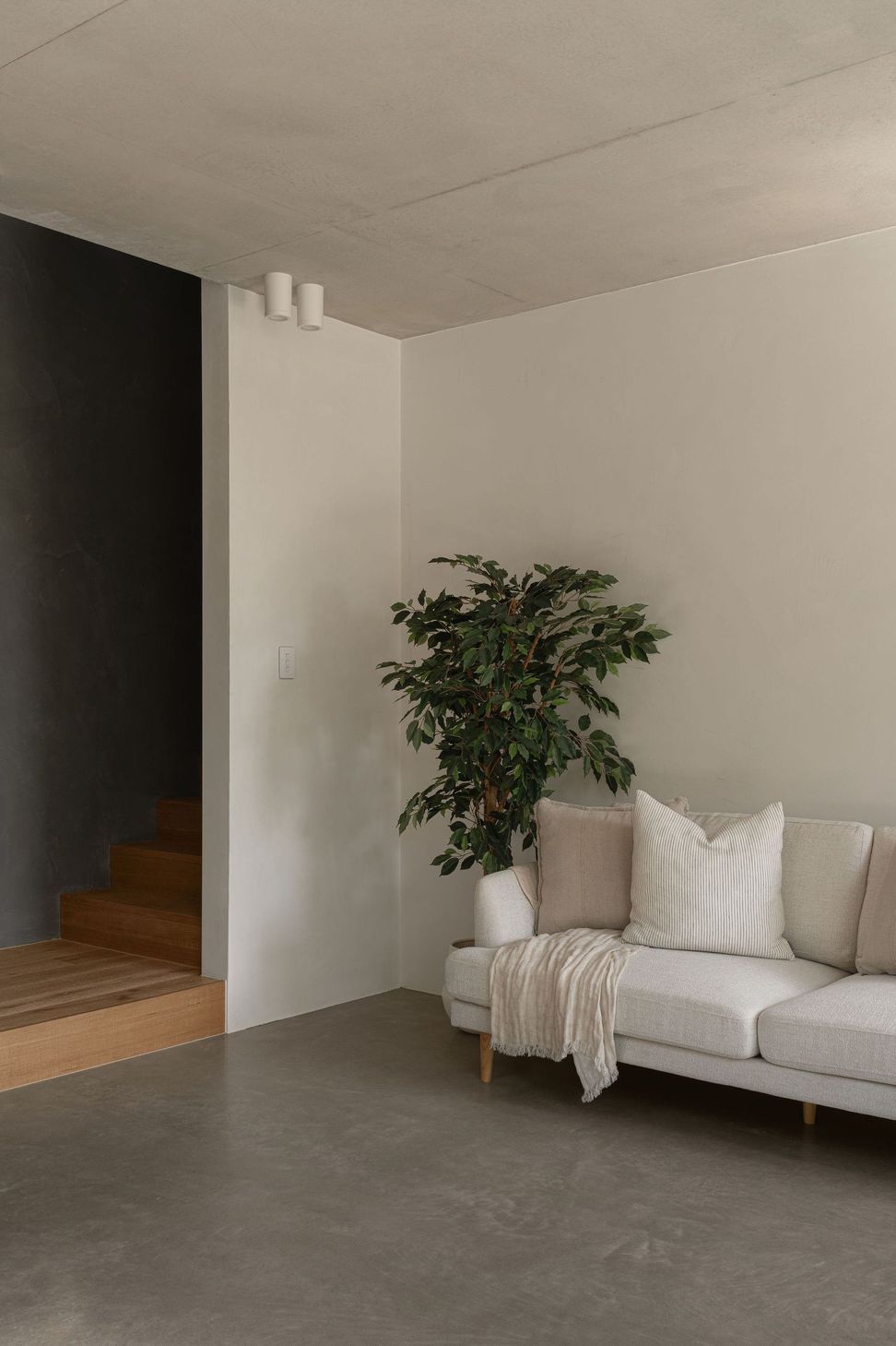The Smith - Living Room. Sofa and indoor plant beside the stair.