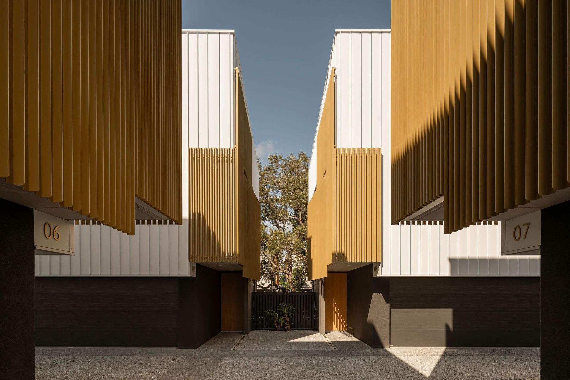 The Smith - Exterior. Looking down the shared driveway between timber screened facades.