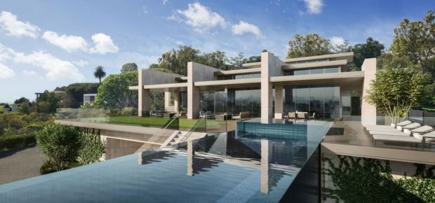 A contemporary multi-level residence viewed from the landscaped grounds, featuring strong horizontal rooflines, pale rendered walls, extensive floor-to-ceiling glazing, and broad concrete terraces. A long reflecting or infinity-edge pool dominates the foreground, with outdoor seating and a covered entertaining area visible behind it. The property is surrounded by mature landscaping under a bright blue sky.