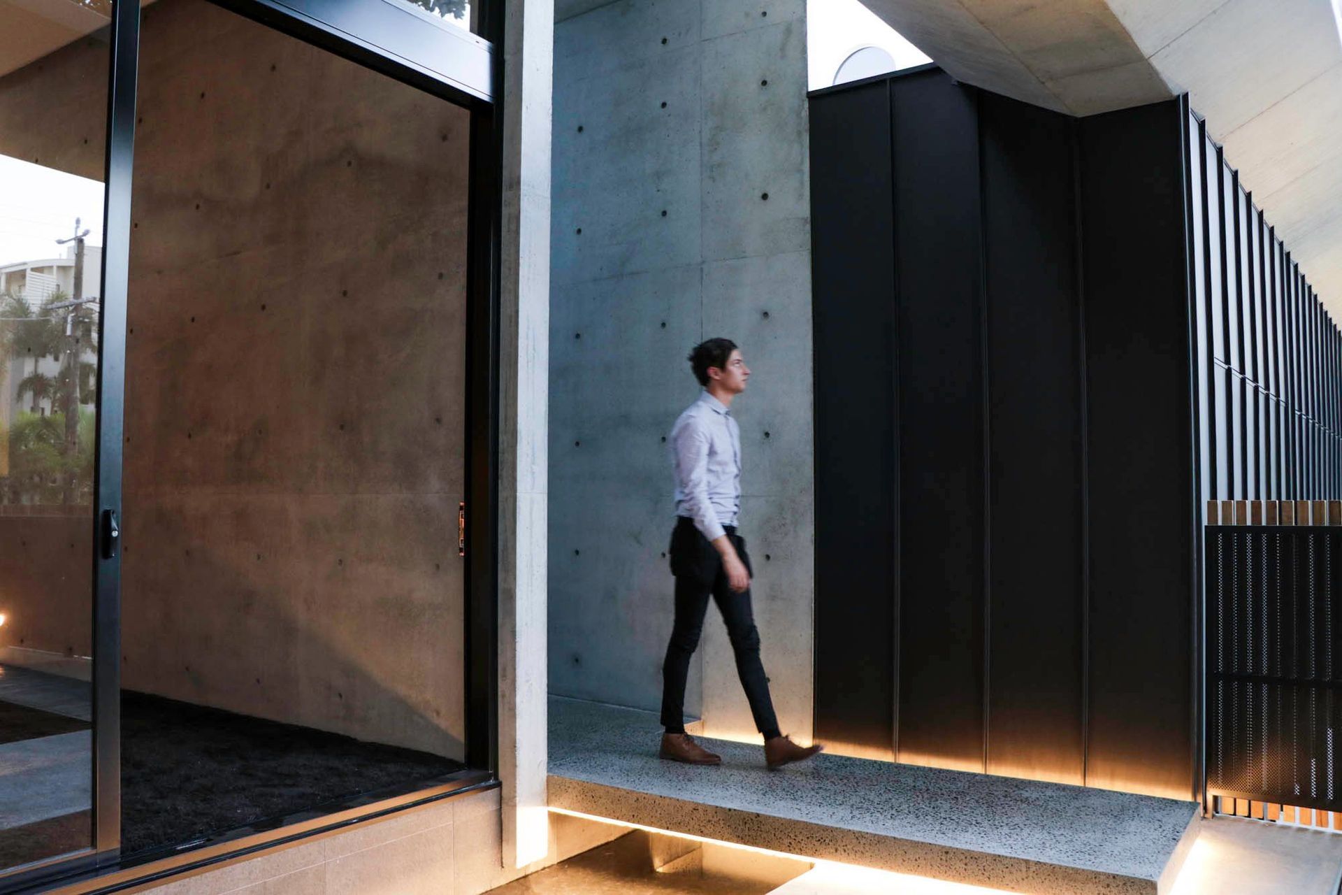 McGovern Residence - Entry. Hallway lined with concrete and timber, glowing with concealed lighting.
