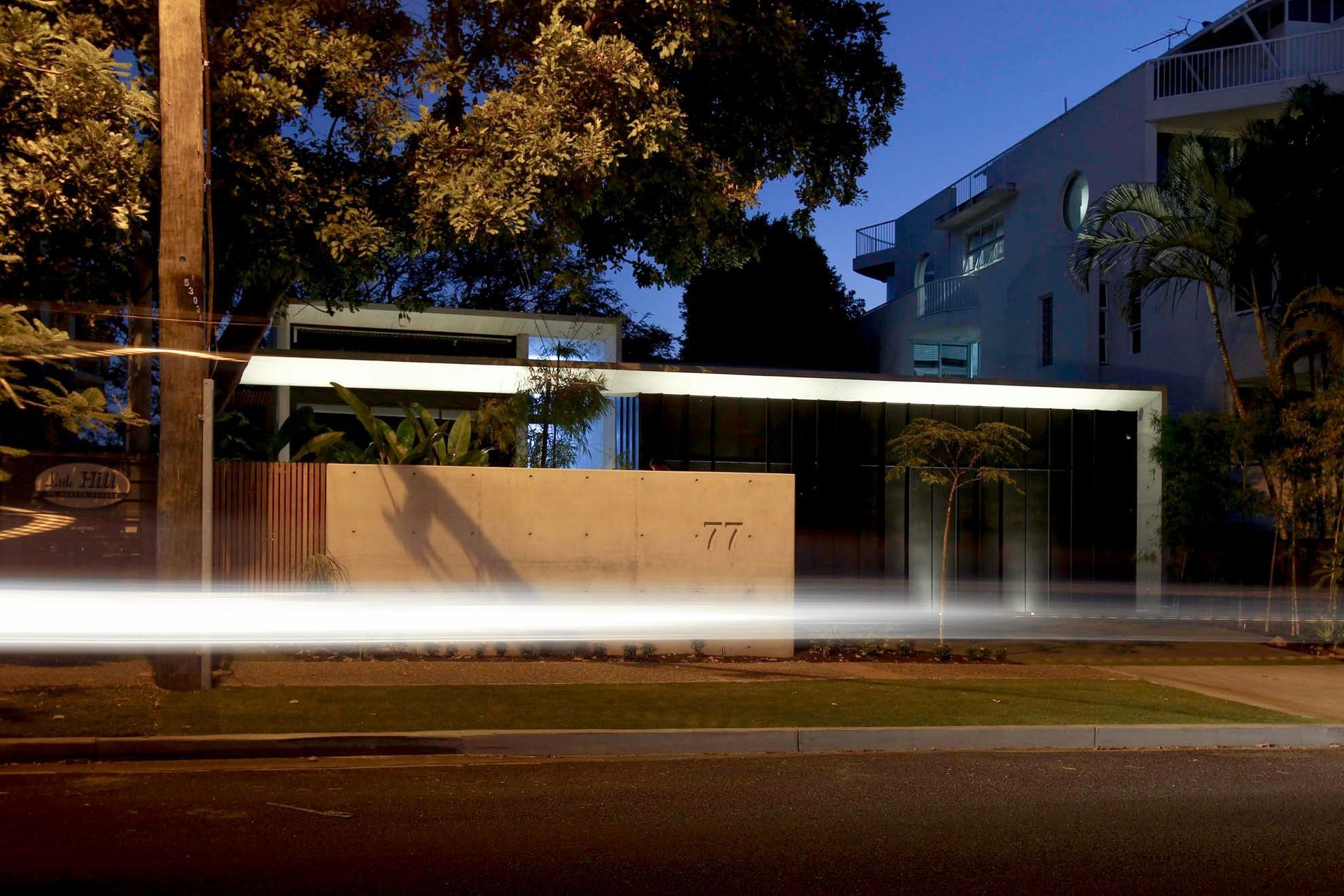 McGovern Residence - Exterior. Street frontage at dusk with a floating lit concrete wall.