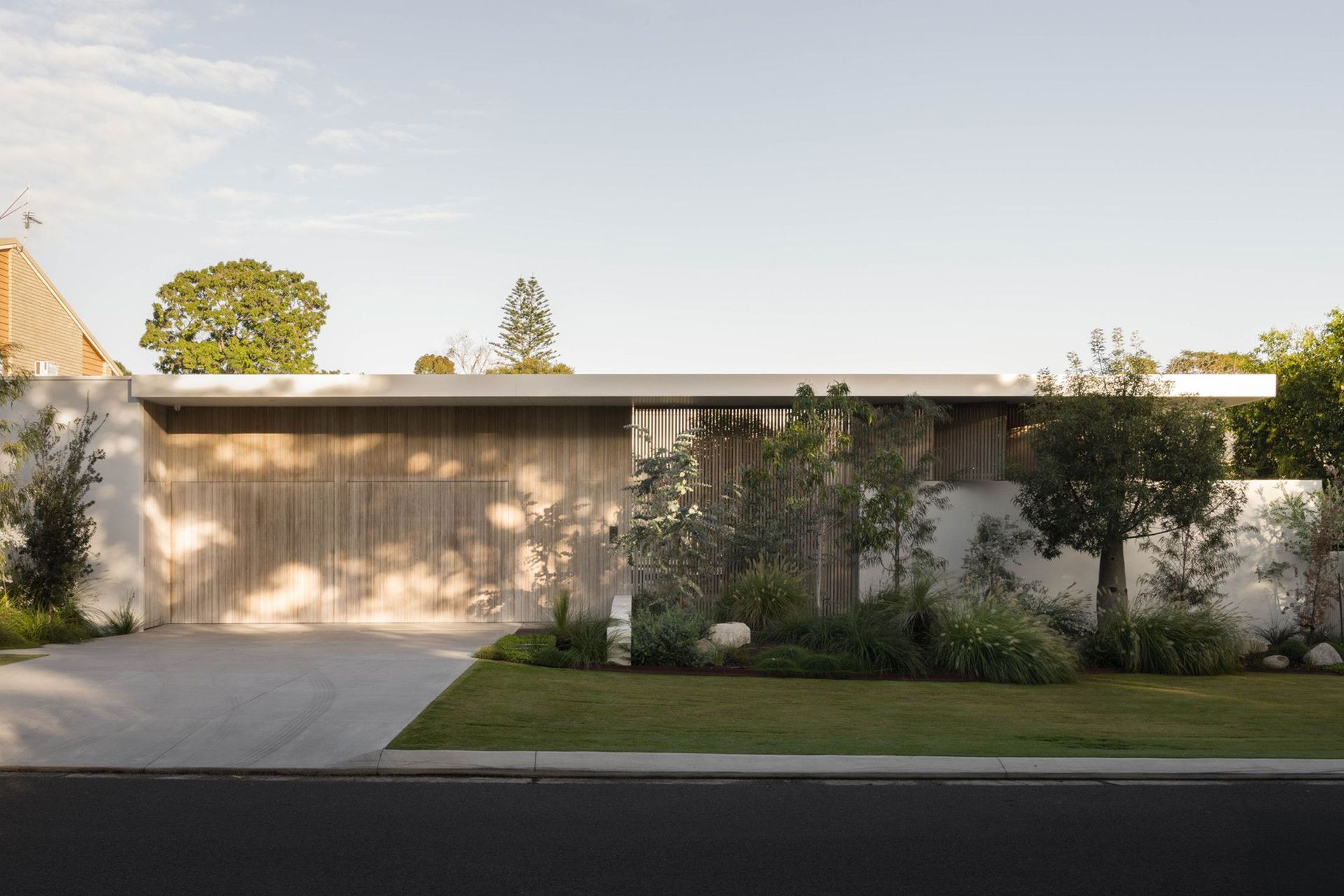 Henderson - Exterior. Street frontage with a timber clad facade and landscaped verge.