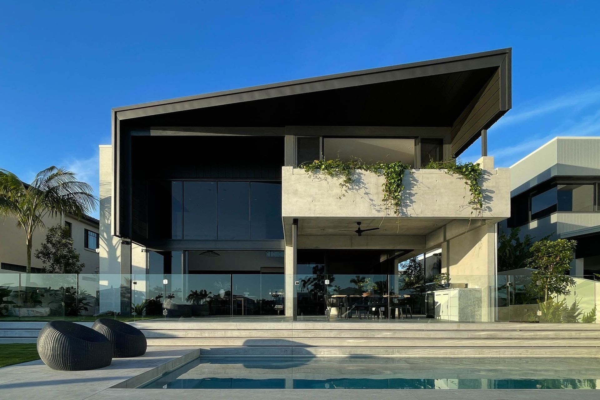 M Residence - Exterior. Rear elevation with a sharp black roof over the pool.