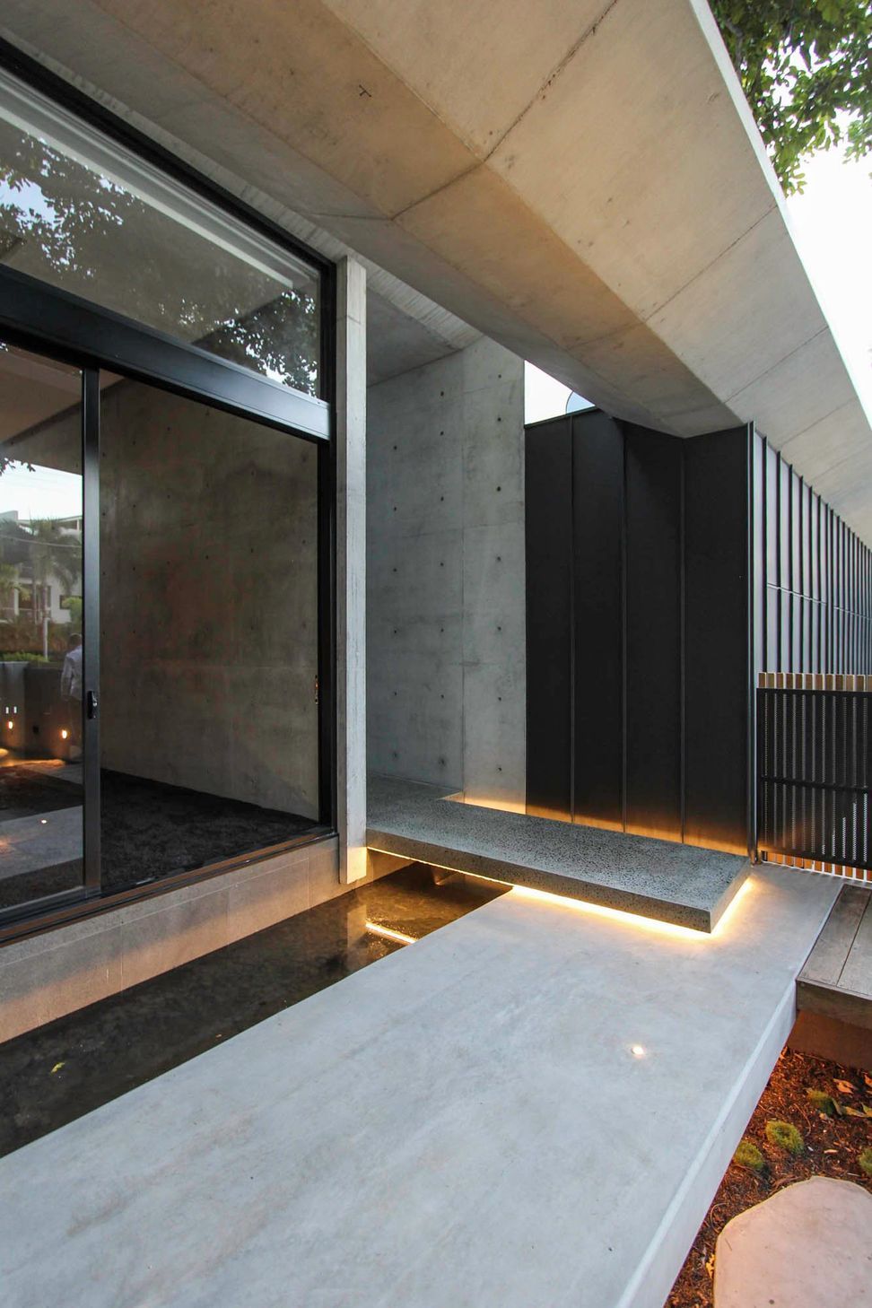 McGovern Residence - Entry. Concrete and black cladding at the entry threshold.