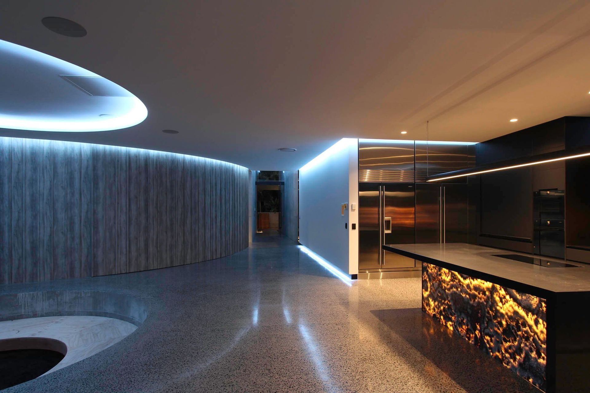 McGovern Residence - Kitchen. Onyx island and curved ceiling detail lit at night.