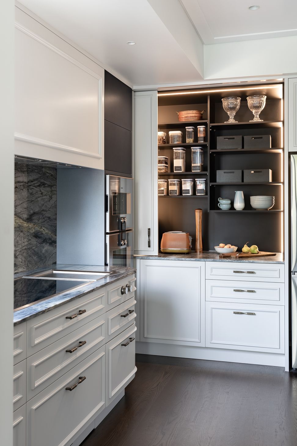 A generous pantry with deep benches hides small appliances inside.  Integrated vertical sensor lighting is incorporated here.