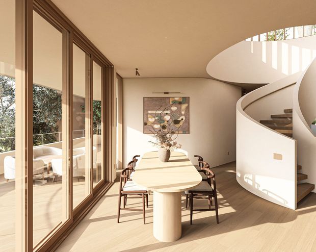 Warm, refined dining area with a long sculptural light-wood table and upholstered timber dining chairs, positioned beside full-height glazed doors opening to an outdoor terrace. A curved contemporary staircase with a white sculpted balustrade rises at the right, and strong sunlight creates geometric highlights across the neutral interior. The room has a generous open-plan feel and a high, curved ceiling void above the stair.