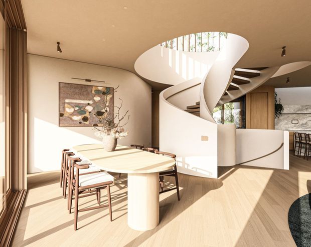 A warm, refined open-plan dining area centered on a sculptural oval dining table and timber-framed chairs. A dramatic white curving spiral staircase with an oval overhead opening dominates the space, with integrated timber cabinetry and glimpses of a kitchen or bar area beyond. Pale timber flooring, creamy plaster walls, expansive glazing, recessed and track lighting, and contemporary artwork create a bright, sculptural interior.