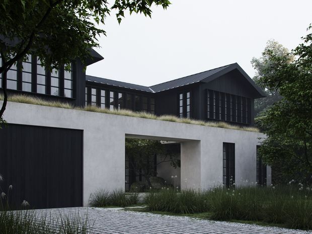 Exterior view of a contemporary multi-level residence set into a landscaped, sloping site. The lower level has a smooth light-grey rendered facade, a large dark garage door, a deep sheltered opening, and tall narrow windows. A planted roof terrace with ornamental grasses sits above it, supporting a dark timber- or metal-clad upper volume with extensive black-framed glazing and a pitched gable roof. The foreground includes patterned pavers and dense grasses, while mature trees frame the house.