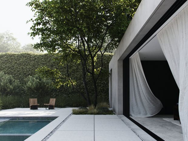 A minimalist contemporary courtyard with a rectangular swimming pool, pale tiled or concrete paving, clipped hedges and mature trees. Two timber lounge chairs sit beside the pool. On the right, a stark white rendered building has a large black-framed opening dressed with sheer white curtains, creating a dramatic indoor-outdoor connection.