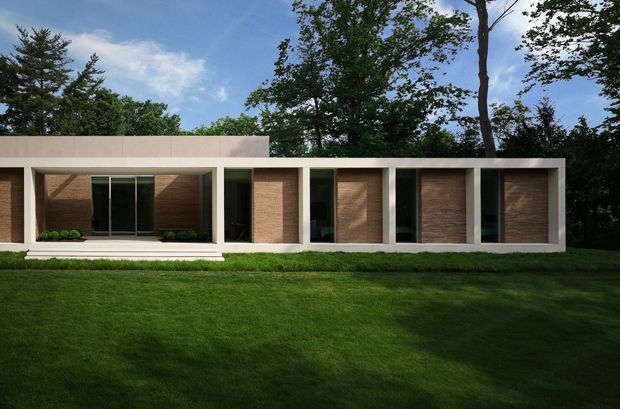 A low, single-storey modern residence set within a landscaped lawn and mature trees. The rectilinear facade combines a white concrete or plaster frame with recessed warm brown brick or textured masonry bays, tall dark-framed glazing, and a flat roofline. A shallow entry terrace and steps run along the front.