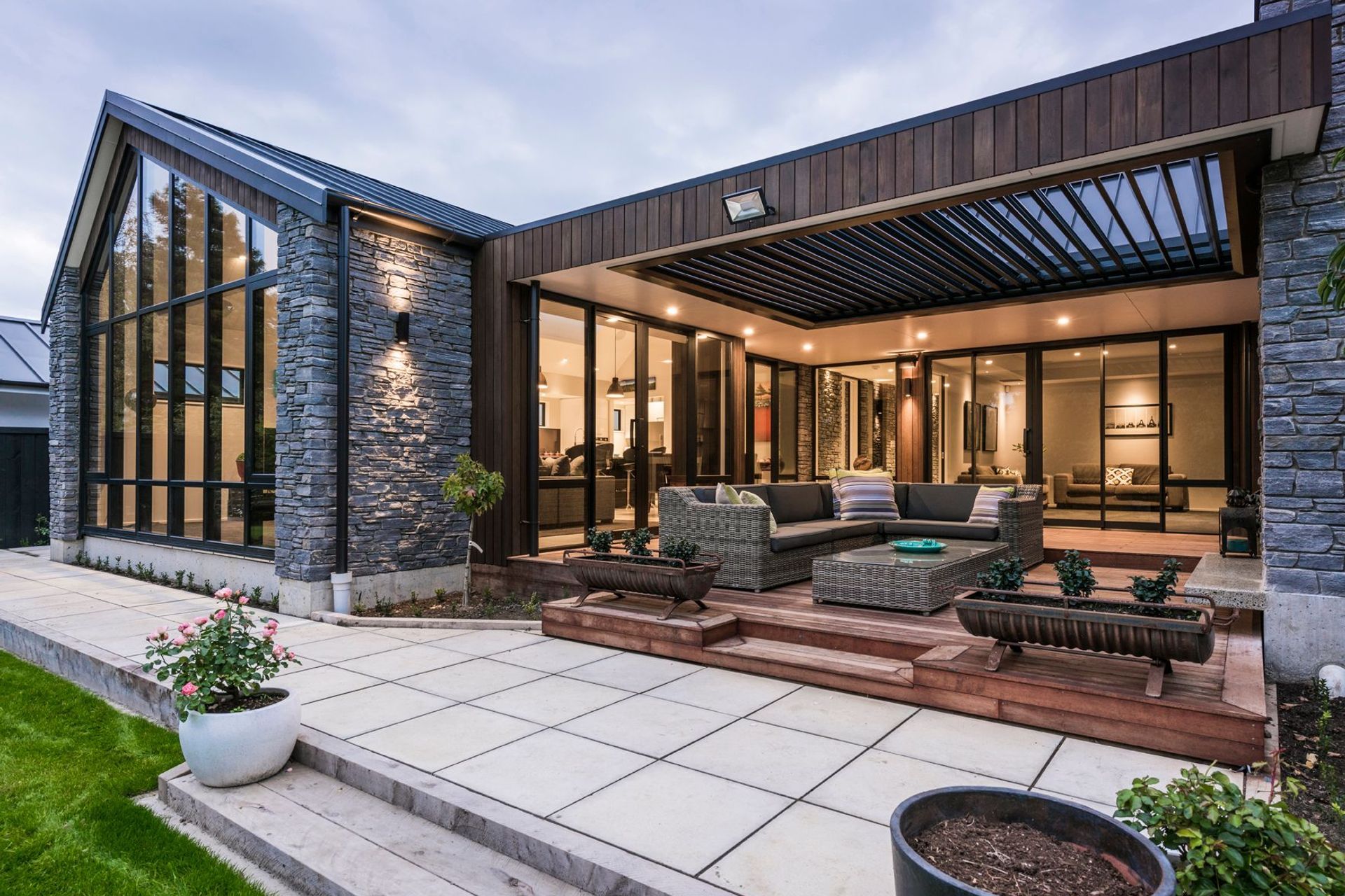 The electric louvred outdoor living area features  a stone fireplace and directly enjoys the view of the stream.