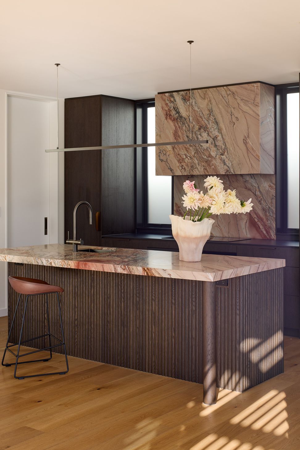 The kitchen's carefully composed material palette of stained oak, granite and natural timber flooring creates a warm and sophisticated centrepiece for family life.