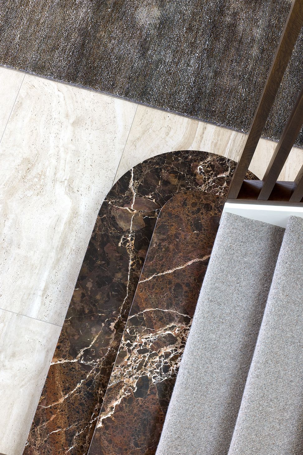 Viewed from above, the entrance staircase reveals the craftsmanship of its marble treads and full-height timber screen. The carefully detailed materials create a refined transition between the home's different levels.