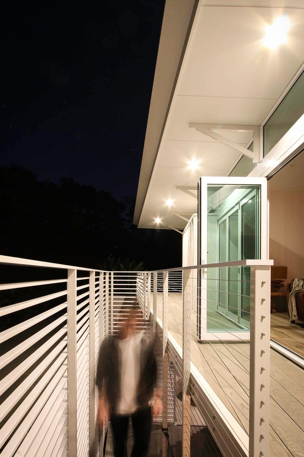 105 Residence - Balcony. Covered balcony with slatted balustrades at night.