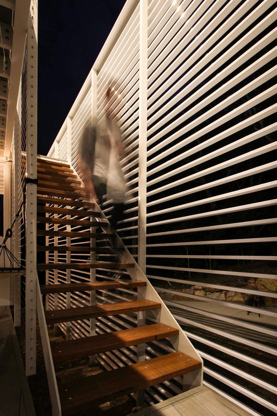 105 Residence - Staircase. Timber stair behind horizontal white slats.