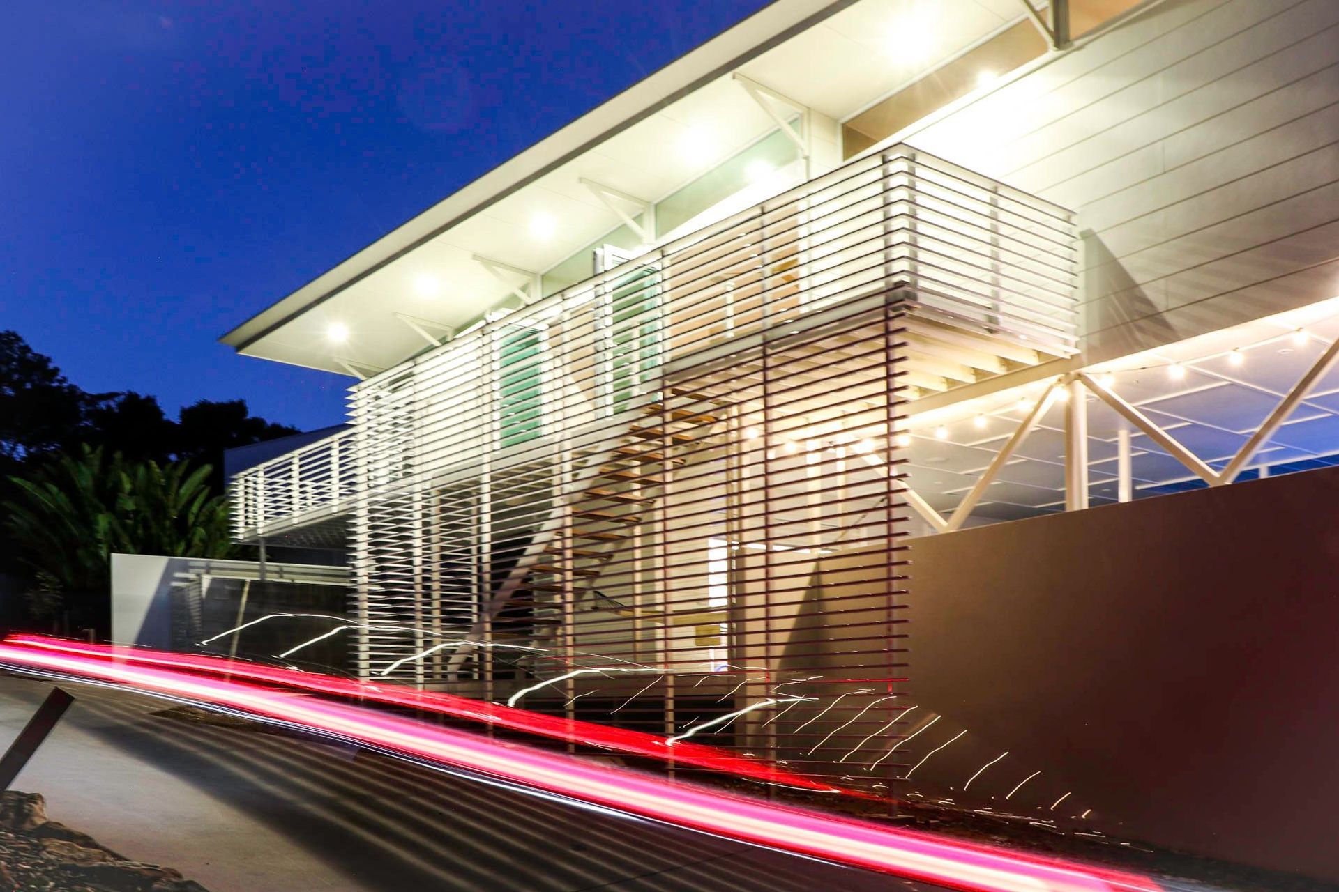 105 Residence - Exterior. External stair and screens glowing at dusk.