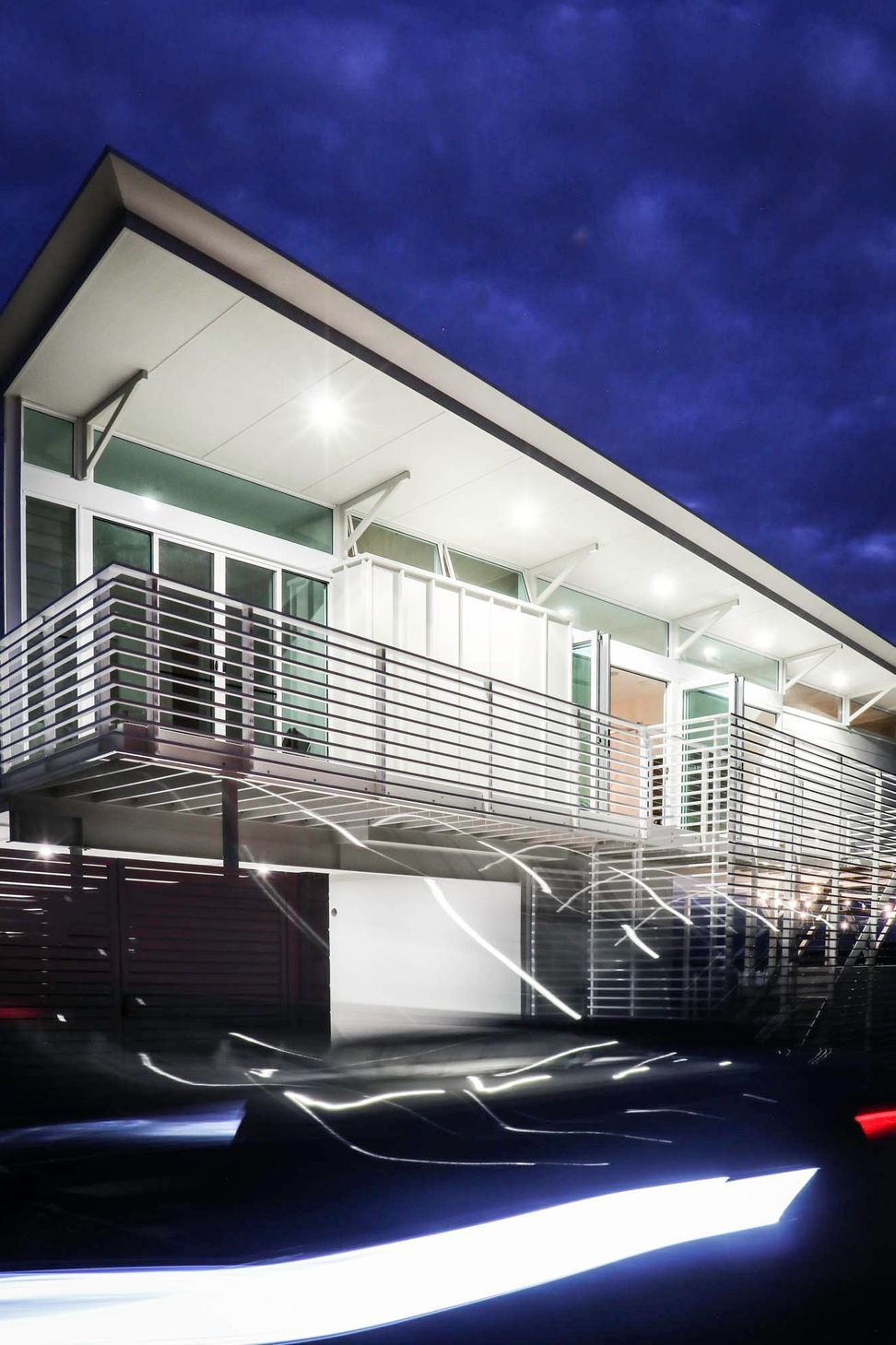 105 Residence - Exterior. Slatted balustrade and deck lit at night.
