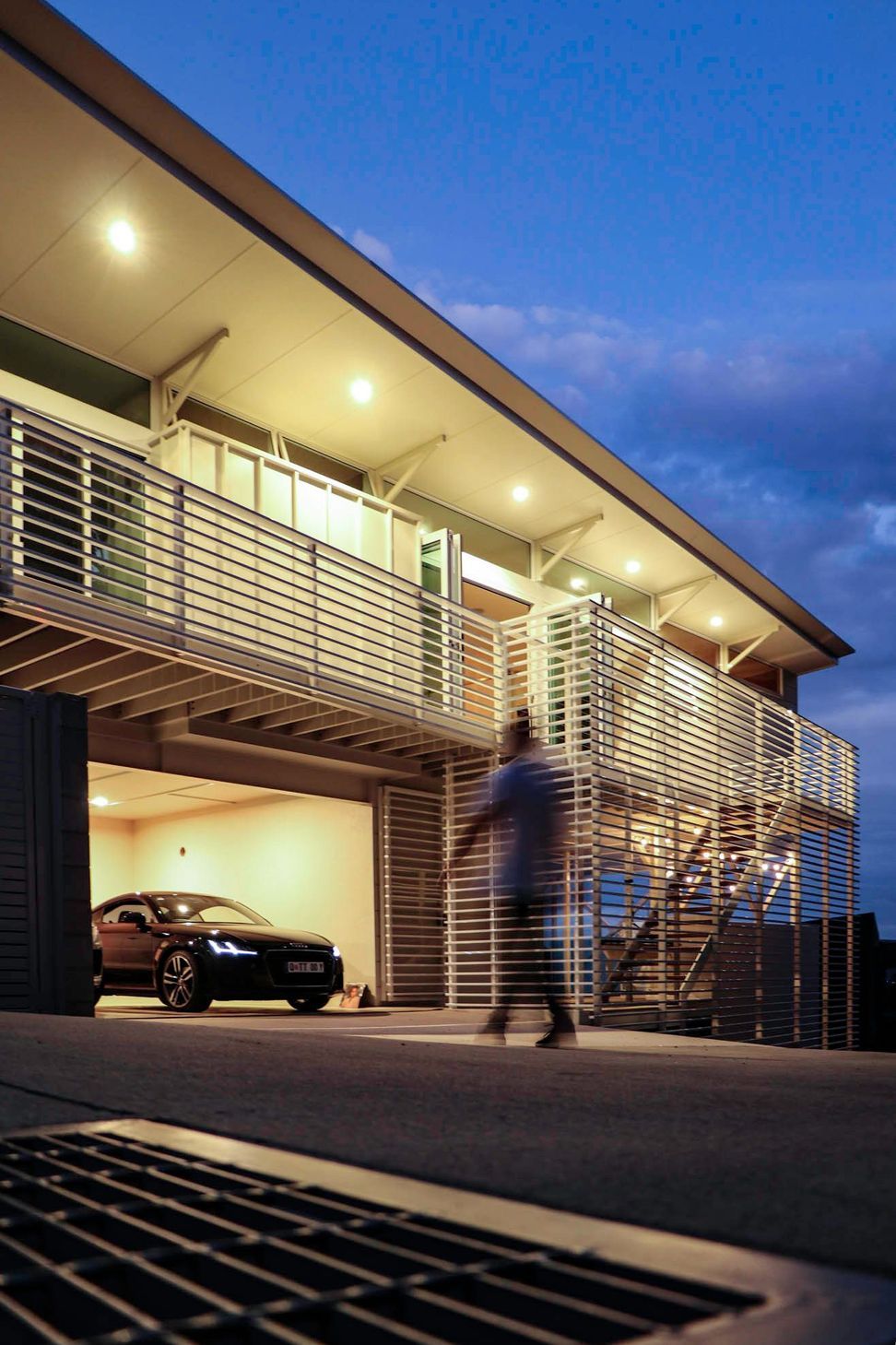 105 Residence - Exterior. Lit garage and deck at dusk.