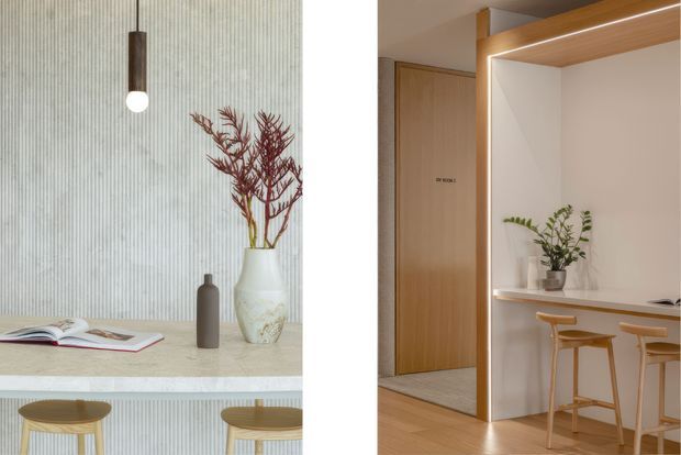 Split view of a refined contemporary interior. The left side shows a pale vertically ribbed wall with a slim pendant light, stone or terrazzo-like ledge, decorative vases and timber stools. The right side shows a warm timber-lined entry and compact built-in breakfast counter with integrated shelving, concealed LED lighting, timber cabinetry, and stools.