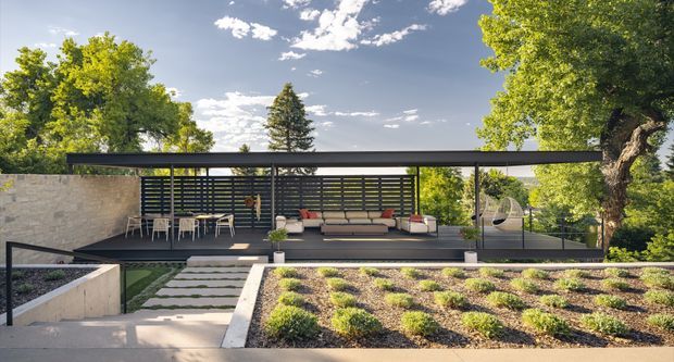 A low, modern pavilion-style residence set within a landscaped garden. The composition features a long flat roof with slender dark metal posts, extensive horizontal louvred glazing, a stone-clad wall, and an open outdoor lounge furnished with sofas and chairs. Stepping stones, raised garden beds, and mature trees frame the minimalist architecture.