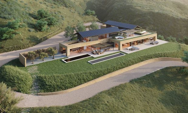 Aerial architectural rendering of a large, low-profile contemporary residence integrated into a steep grassy hillside. The multi-wing building has dark pitched metal roofs, extensive glazing, warm timber-toned walls, broad terraces, planted roof areas, outdoor seating, long narrow reflecting pools, and landscaped paths and driveways.