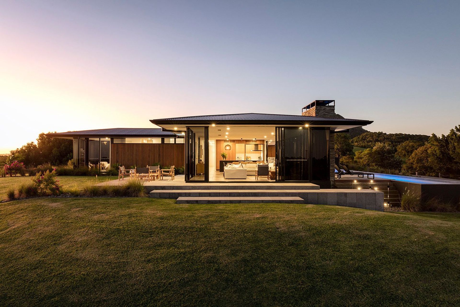 Clark Residence - Exterior. Glazed living pavilion glowing at sunset.