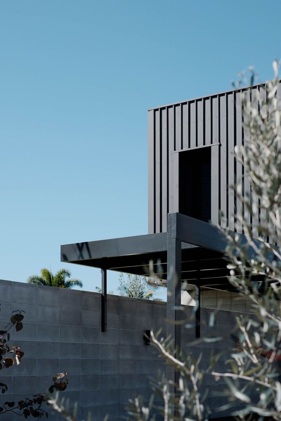 Seabrook and Borg Residence - Exterior. Steel pergola edge against dark vertical cladding.