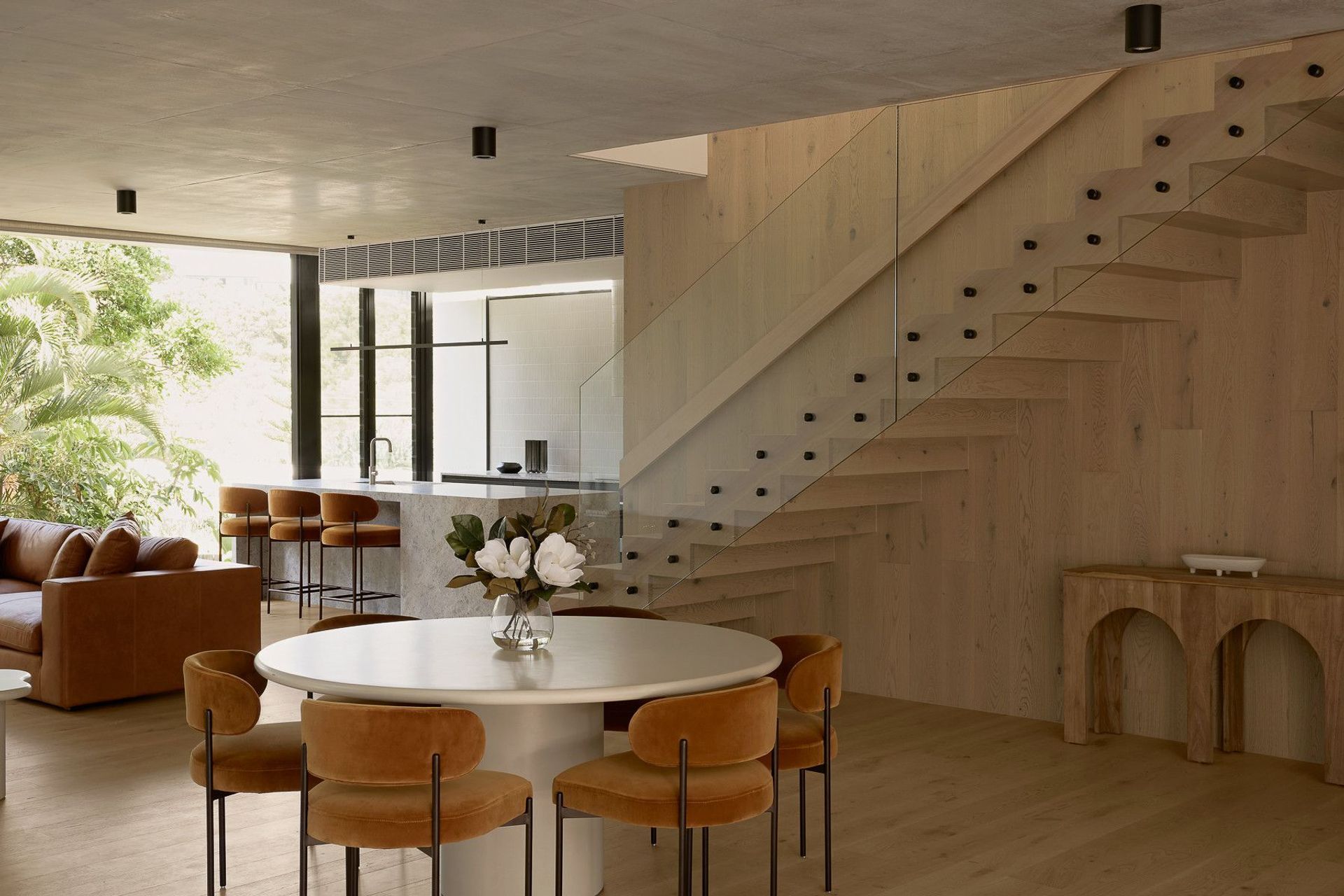 Wildflower Residence - Dining Room. Round dining table beneath a floating timber stair.