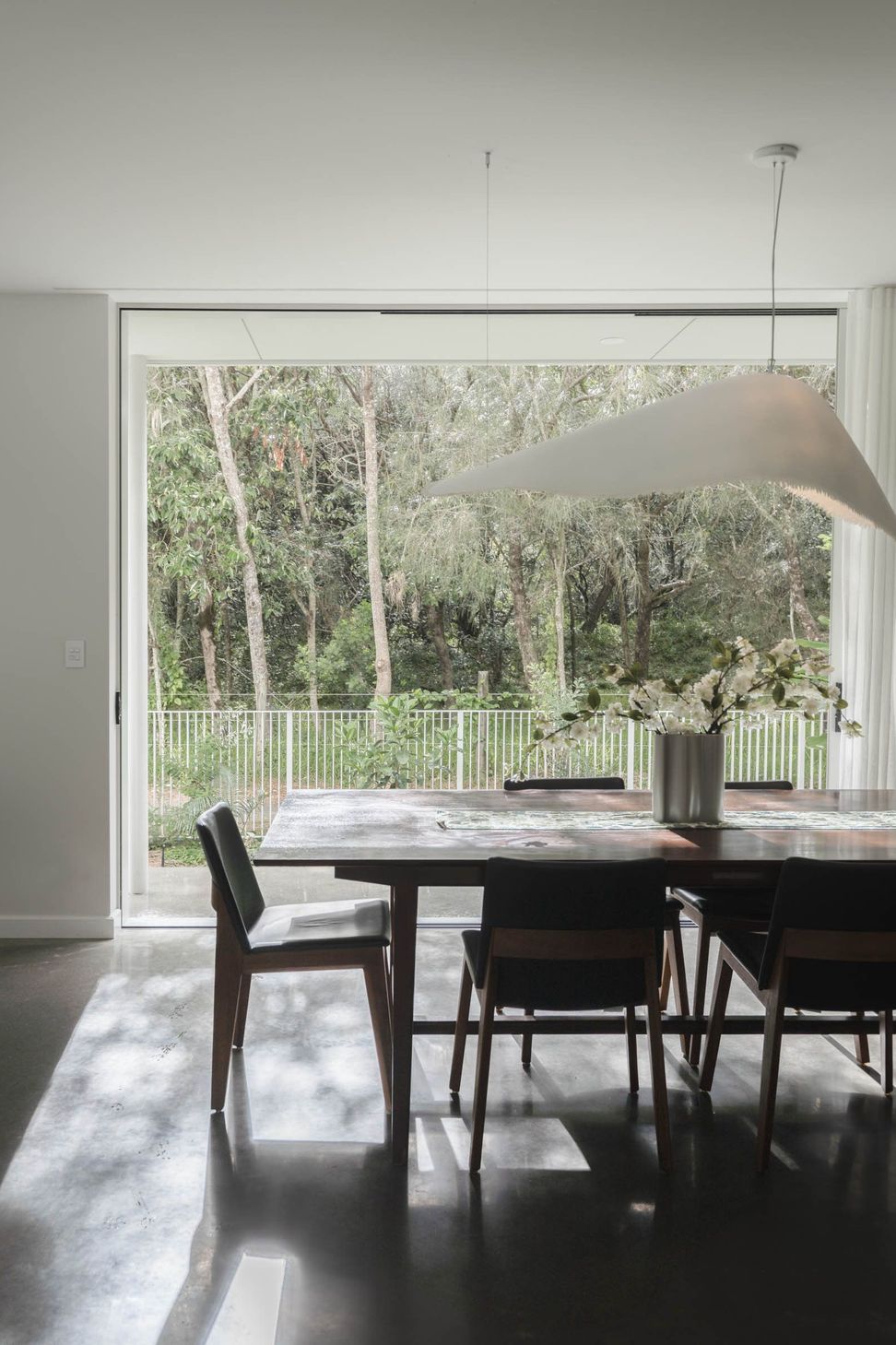 Eleutheria - Dining Room. Dining table beneath a sculptural pendant, opening to the garden.