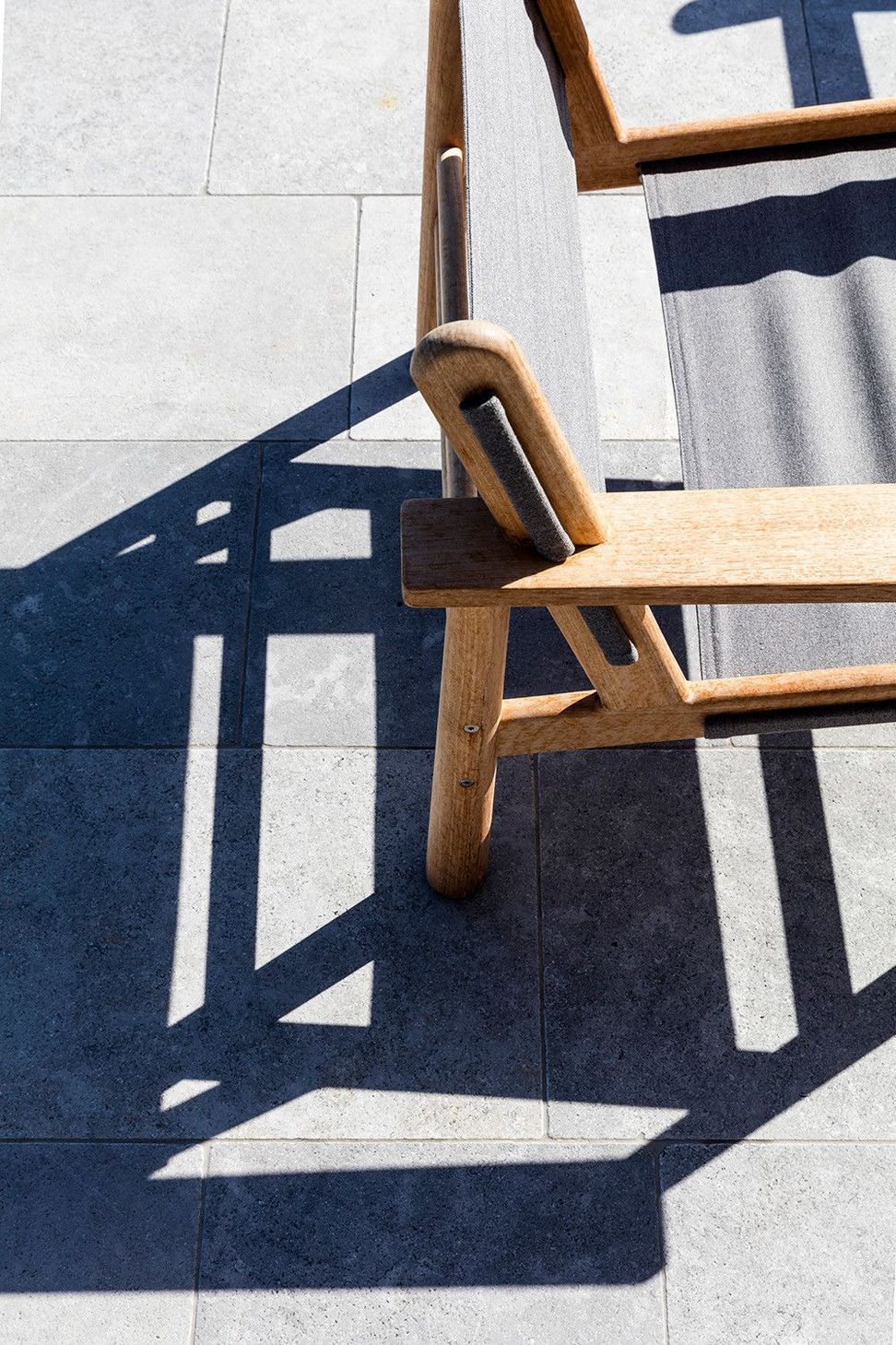Clark Residence - Living Room. Timber chair casting shadows on the stone floor.