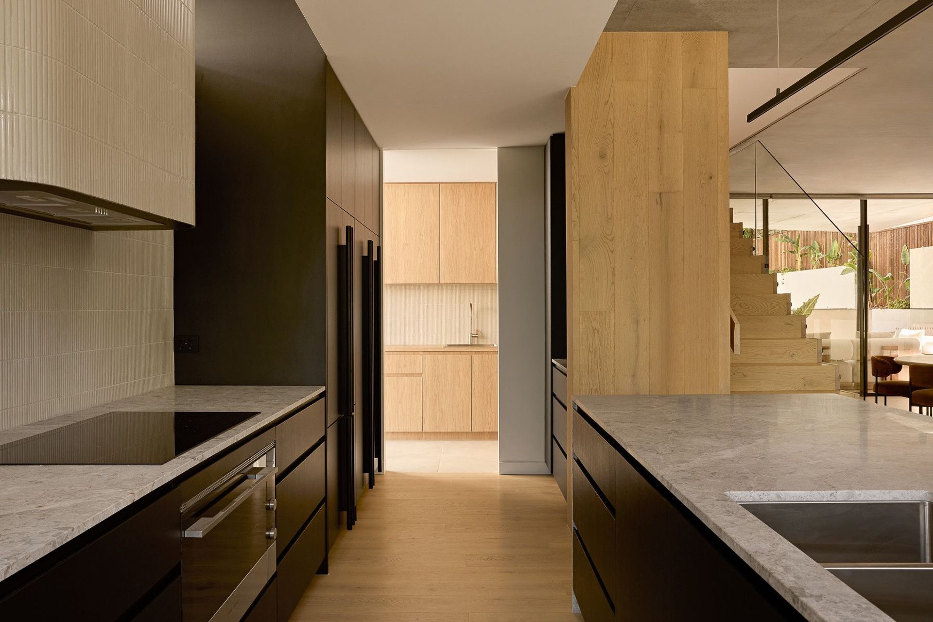Wildflower Residence - Kitchen. Galley view through timber joinery to the laundry.