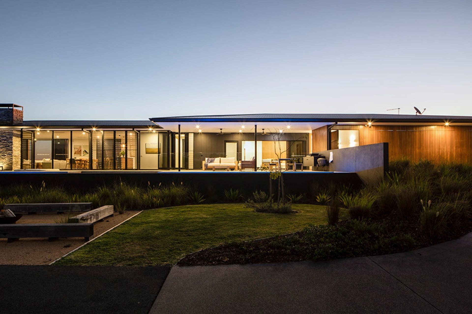 Clark Residence - Exterior. The home lit up at dusk across the lawn.