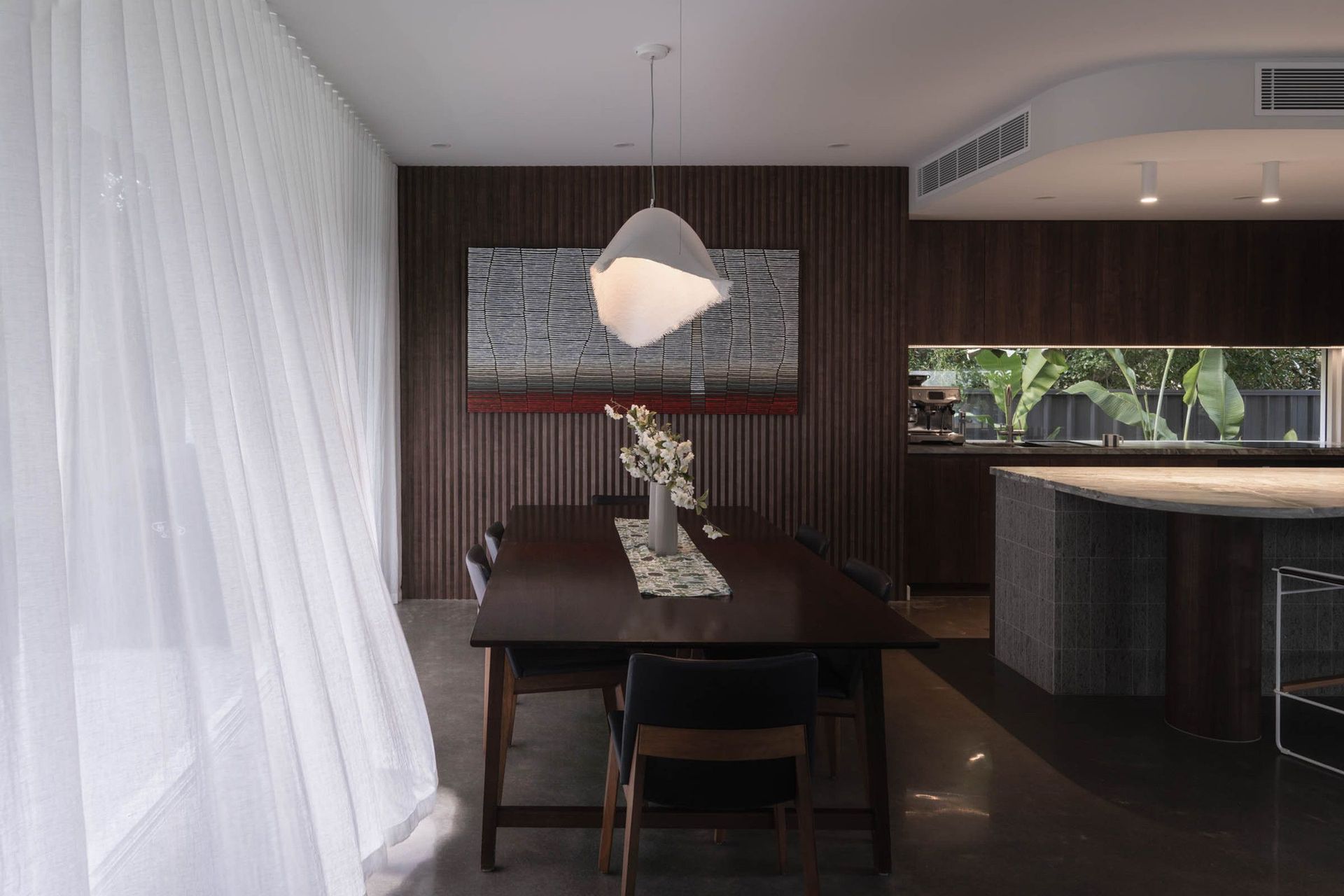 Eleutheria - Dining Room. Moody dining space with a paper pendant and timber walls.