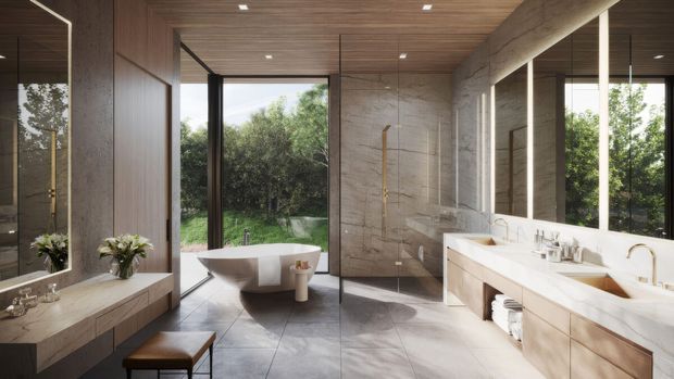 Spacious contemporary bathroom with a freestanding white bathtub beside full-height glazing, a long double vanity with pale wood cabinetry and white basins, large-format grey stone-look wall and floor finishes, and a warm timber ceiling. Mirrors reflect the vanity and tub, while garden greenery is visible outside.