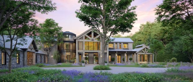 A wide architectural rendering of a multi-wing contemporary residence set within a landscaped, tree-filled site. The building features dark stone walls, extensive glazing, warm timber accents, steep gabled roof forms, and a prominent central double-height glazed section. A cylindrical dark-clad tower-like volume and several connected wings create a complex multi-building composition, approached across a broad garden and paved forecourt at dusk.
