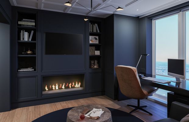 A dark, refined home office with built-in navy-black panelled cabinetry, open display shelving, a wall-mounted television, and a linear gas fireplace. A modern desk and brown upholstered swivel chair sit beside full-height glazing overlooking a blue coastal or waterfront view. The room has a geometric coffered ceiling, timber flooring, a dark circular rug, and understated contemporary lighting.