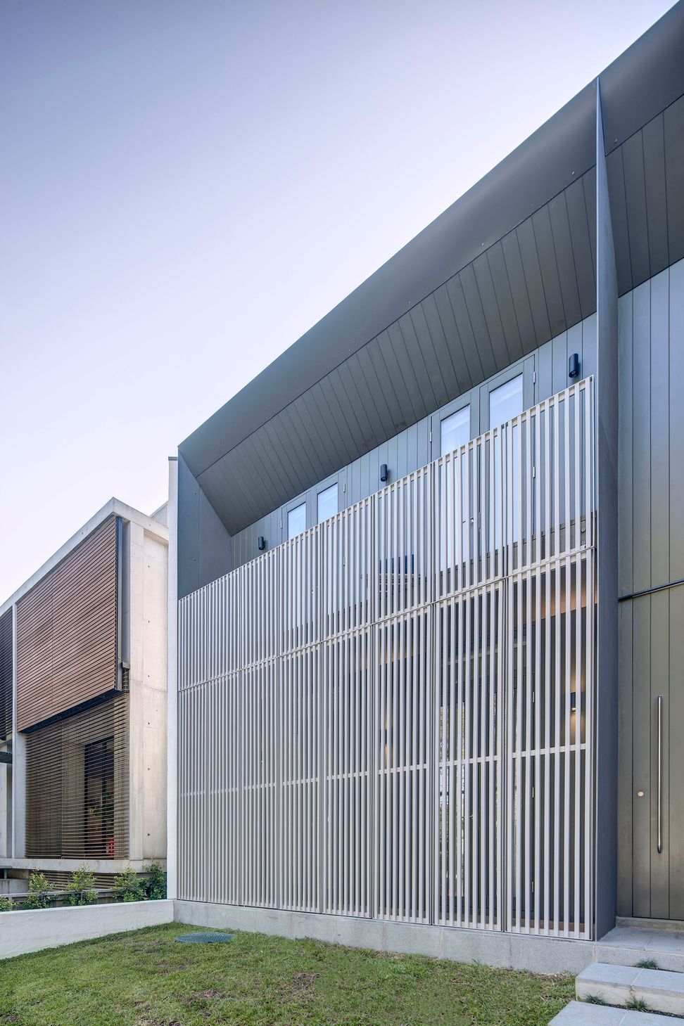 Hinged screens cloak the front elevation, mediating the interface with the street.