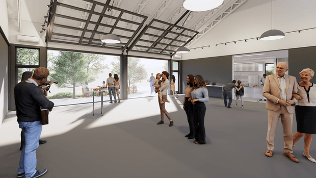 A spacious, bright contemporary commercial interior resembling an event, gallery, or showroom space. The open-plan room has a polished grey floor, dark grey feature walls, extensive glazing opening to an outdoor terrace, exposed white structural ceiling elements, suspended black-framed rectangular ceiling grids, track lighting, and multiple pendant lights. People are dispersed throughout the space, with a service or kitchen-like area visible at the rear.