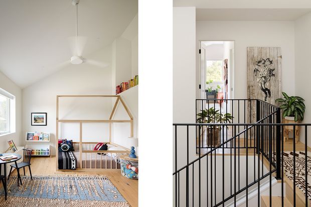 Split view of a bright residential interior showing a children's bedroom or playroom on the left and an upstairs landing or stairway on the right. The spaces feature white walls, pale timber flooring, a pitched ceiling with a ceiling fan, open timber shelving, colourful books and toys, patterned rugs, black metal stair balustrades, indoor plants, and framed artwork.