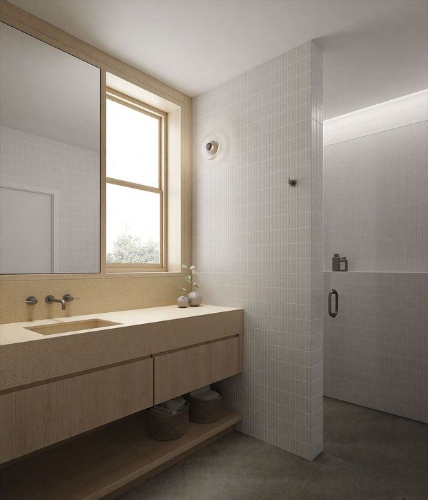 A calm, contemporary bathroom with a long floating timber vanity, integrated pale stone or solid-surface benchtop and basin, wall-mounted taps, a large mirrored cabinet, and open shelving beneath. Fine light-grey mosaic tiles cover the walls, while the floor is a dark smooth finish. A timber-framed window provides natural light, and a partially concealed glass shower enclosure is visible to the right.