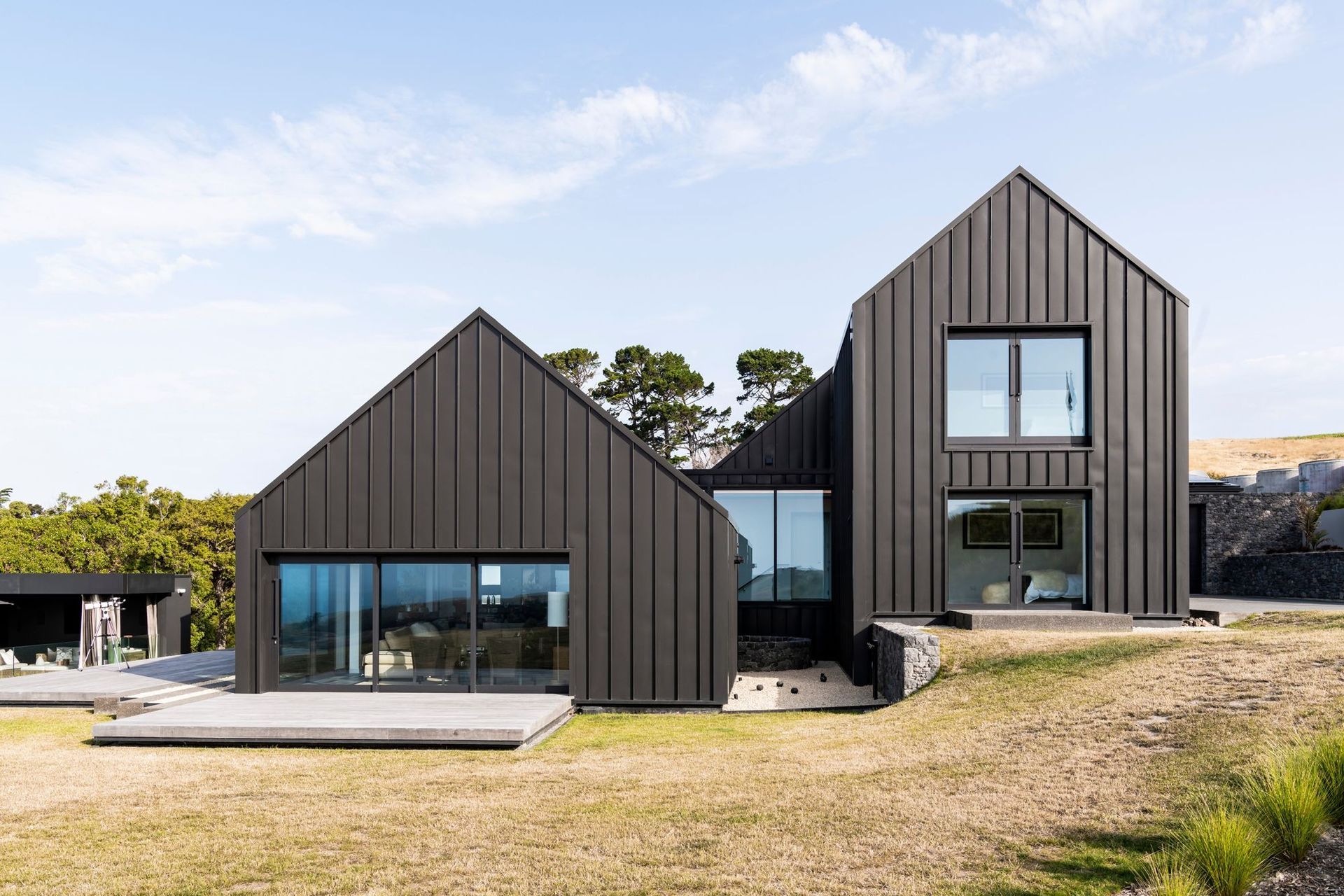 The gable form containing the living spaces steps down from the two-storey gable form containing accommodation.