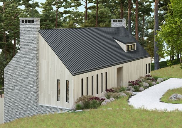 A contemporary single-storey house set among mature pine trees on a landscaped, gently sloping site. The building has pale vertical cladding, a steep dark corrugated gable roof with a dormer window, tall narrow windows, and a prominent grey masonry chimney. A curved light-coloured path leads through naturalistic grasses and shrubs toward the entrance.