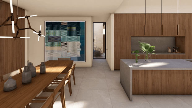 A warm contemporary open-plan kitchen and dining area with extensive walnut-toned timber cabinetry and a matching dining table. The kitchen features a large island with a pale stone benchtop, dark splashback, integrated cabinetry, and slim pendant lights. A long timber dining table with sculptural vases sits beneath a linear contemporary chandelier, while a large geometric artwork and a framed mirror add visual interest. Pale tiled flooring and soft neutral walls create a refined, calm interior.
